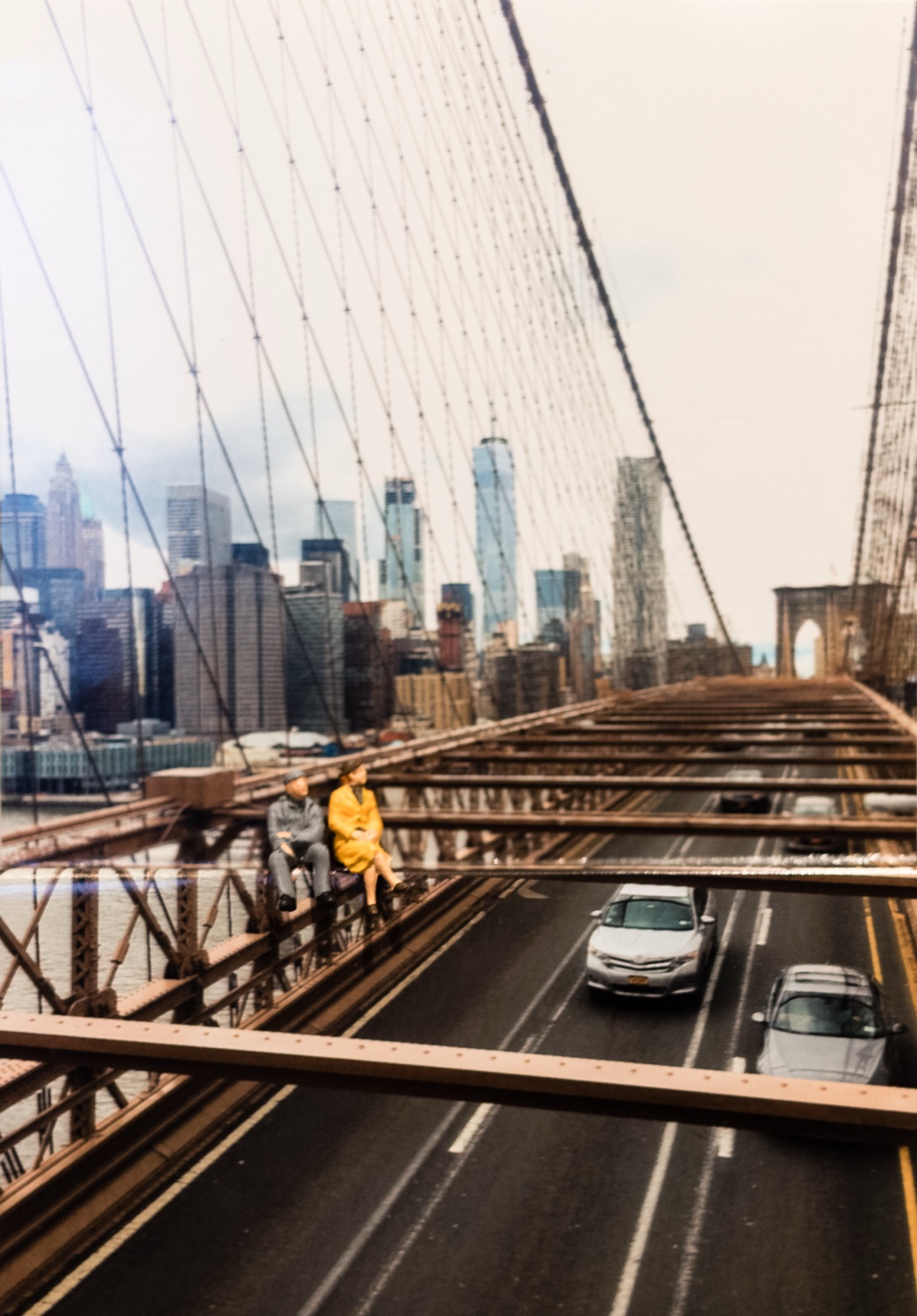 Diorama: Miniaturpaar sitzt auf einem Träger der Brooklyn Bridge über dem Verkehr, im Hintergrund die Skyline von Manhattan