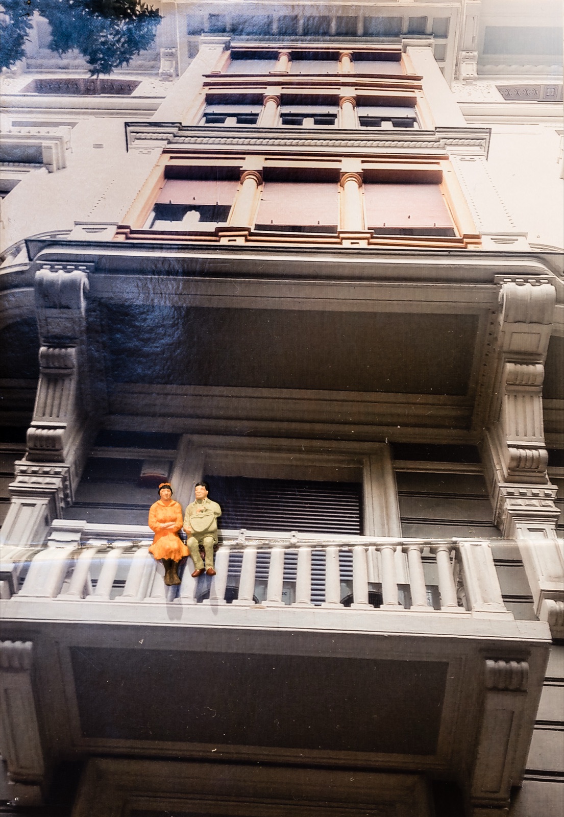 Diorama: Miniaturpaar sitzt auf einer Balkonbrüstung vor einer historischen Fassade