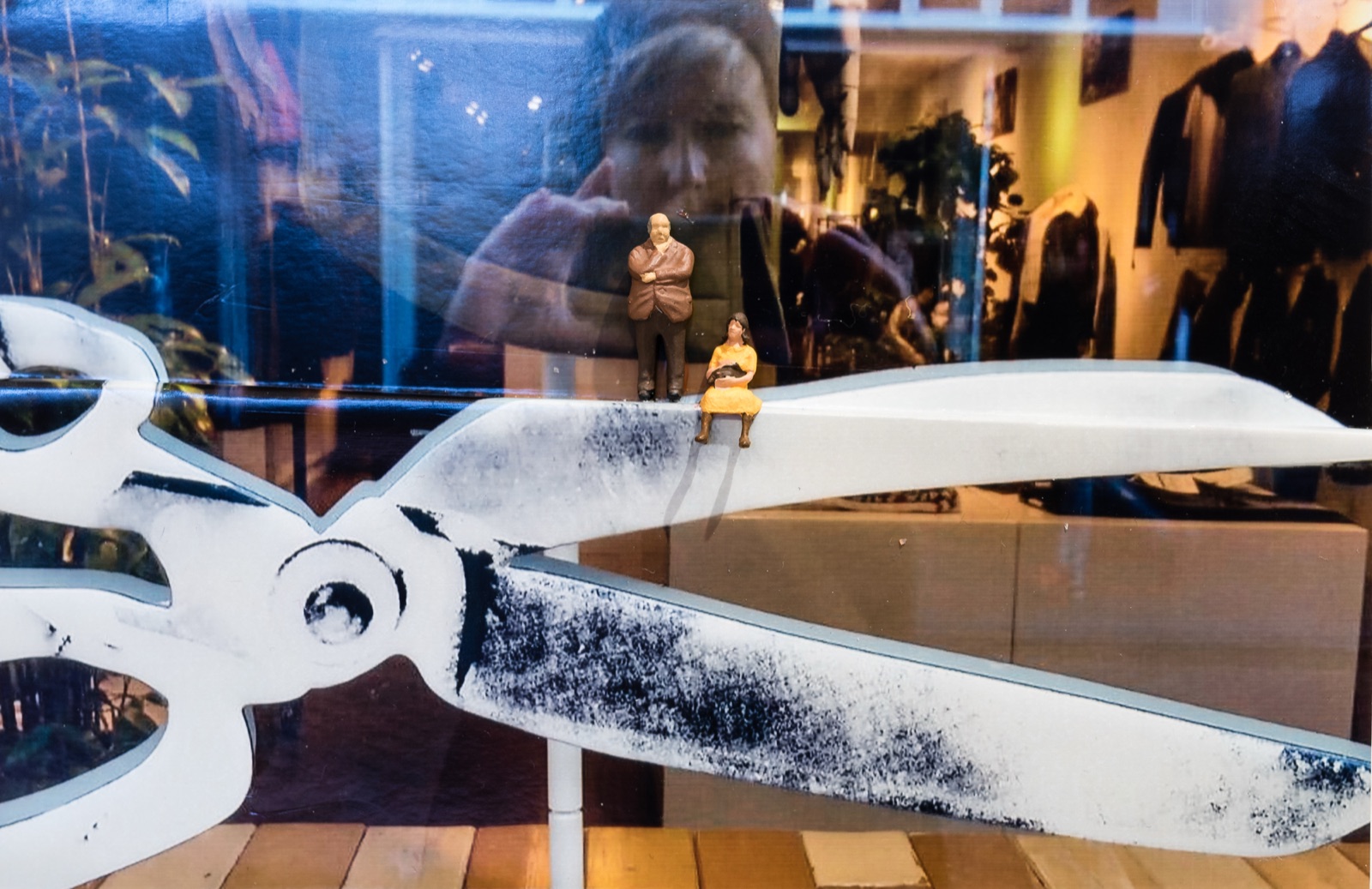 Diorama: Zwei Miniaturfiguren auf einer überdimensionalen Schere in einem Schaufenster